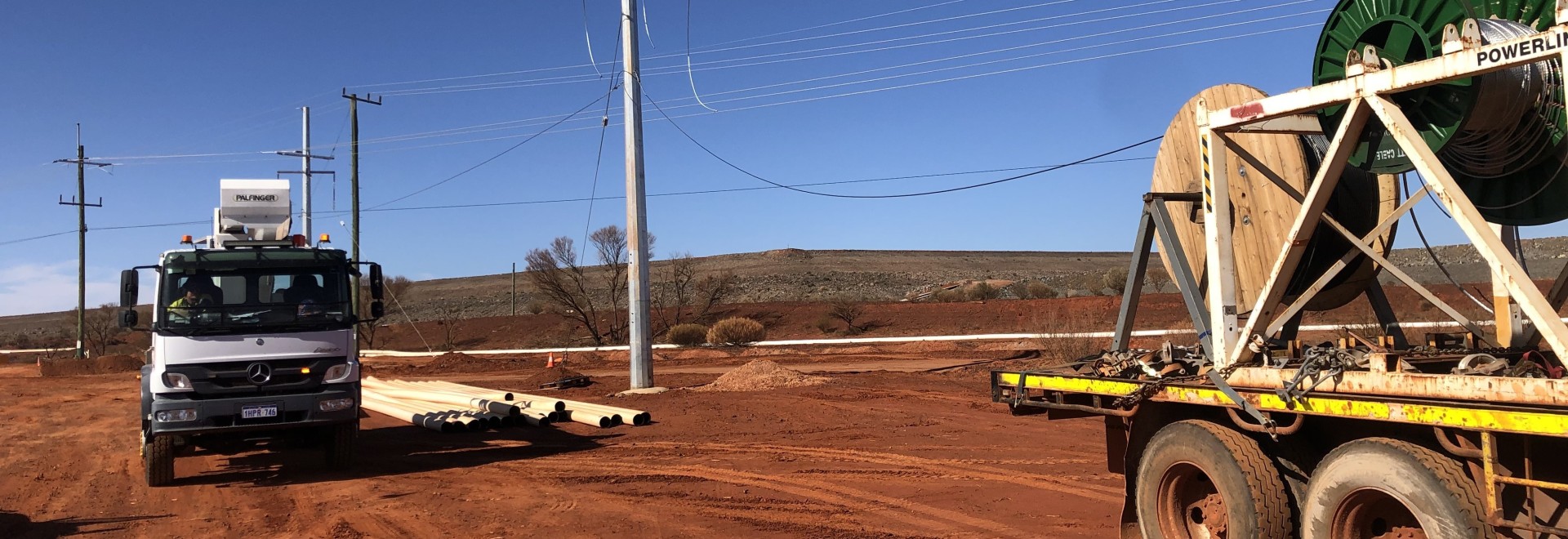 2 Trucks on red dirt next to powerlines